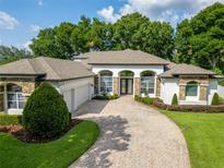 Stunning home with a curved driveway, attached garage, stone accents, and arched windows at 16951 Florence View Dr, Montverde, FL 34756
