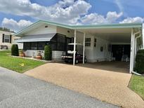 Charming home featuring a covered carport and well-maintained landscaping with vibrant green grass at 175 Hibiscus Way, Leesburg, FL 34748