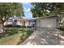 Charming single-story home with an attached garage, blue awnings, and well-maintained landscaping at 2003 Cordero Ct, The Villages, FL 32159