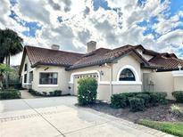 Beige single-story home featuring a brown tile roof, arched window and well maintained landscaping at 26612 Bella Vista Dr, Howey In The Hills, FL 34737