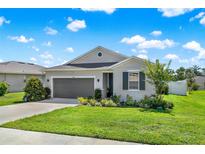 Charming single-story home featuring a well-manicured lawn, landscaped garden beds, and an attached two-car garage at 31760 Broadwater Ave, Leesburg, FL 34748
