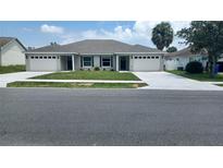 Charming duplex with manicured lawn and gray roof at 435 Woodview Dr, Tavares, FL 32778