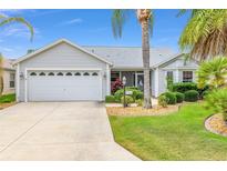 Charming single-story home featuring an attached two-car garage and lush landscaping with mature palm trees at 762 Turbeville Ter, The Villages, FL 32162