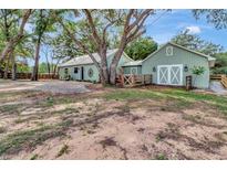 Charming home exterior with green siding, mature trees, a brick patio, and barn-style architecture at 10330 Dwights Rd, Clermont, FL 34714