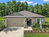 Charming home featuring manicured landscaping, two-car garage, and a welcoming entrance with tasteful decorative elements at 12952 Del Lago Dr, Astatula, FL 34705