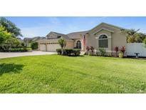 Charming home with a lush green lawn, beautiful landscaping, and a three-car garage at 13100 Lakewind Dr, Clermont, FL 34711