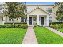 Charming townhome with a well-maintained lawn, brick walkway, and inviting front porch at 14421 Vashons Way, Winter Garden, FL 34787