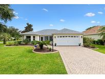 Charming single-story home with a well-manicured lawn, paver driveway, and a two-car garage at 1514 Vandam St, The Villages, FL 32162