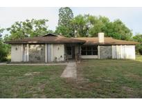 Single-story home showcasing a ranch-style design with a brown roof, neutral paint, and a stone accent at 15587 Se 150Th Ave, Weirsdale, FL 32195