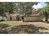 Charming single-story home with a well-manicured lawn, mature trees, and attached two-car garage at 15837 Hidden Lake Cir, Clermont, FL 34711