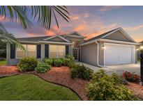 Charming single-story home featuring manicured landscaping, a two-car garage, and a welcoming entrance at 1910 Quiet Oak Ct, The Villages, FL 32162