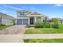 Charming home featuring a well-manicured lawn, an attached two-car garage, and a welcoming front porch with decorative pillars at 2025 Axel St, Minneola, FL 34715
