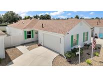 Charming single-story home featuring white siding, a brown roof, green shutters, and a well-manicured lawn at 2050 Duval Ct, The Villages, FL 32162