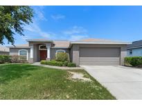 Charming single-story home with a well-maintained lawn and inviting front entrance with mature landscaping at 211 Highland Meadows Ct, Davenport, FL 33837