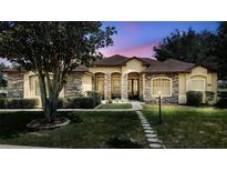 Charming stone and stucco home with landscaped yard, paver walkway, and arched entryway on a well maintained lawn at 21206 Canoe Pass St, Clermont, FL 34715