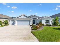 Charming single Gathering home featuring a three car garage, mature landscaping and a covered entryway at 2321 Demarco Dr, The Villages, FL 32163