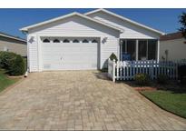 Charming single-story home with a white picket fence, brick driveway, and well-maintained lawn at 2388 Branchville Ter, The Villages, FL 32162