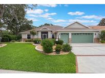 Charming single-story home with a well-manicured lawn, beautiful landscaping, and a two-car garage at 25236 Waterbridge Ct, Leesburg, FL 34748