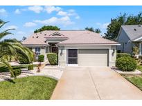 Charming home featuring a well-manicured lawn, lovely landscaping, and an attached two-car garage at 27018 Nature View St, Leesburg, FL 34748