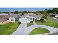 Charming single-story home featuring a well-manicured lawn and a circular driveway at 2785 Privada Dr, The Villages, FL 32162