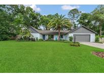 Charming single-story home boasts a lush green lawn and mature landscaping with palm trees at 717 Southeast 46Th Ct, Ocala, FL 34471