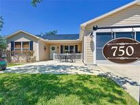 Charming single-story home with beige siding, black shutters, and a cozy front patio with outdoor seating at 750 Eden Pl, The Villages, FL 32162