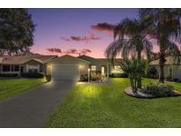 Charming single-story home with a well-manicured lawn and inviting curb appeal at sunset at 851 Evelynton Loop, The Villages, FL 32162