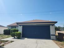 Charming single-story home with blue garage door, landscaped front, and bright blue skies at 112 Arlington Ct, Haines City, FL 33844