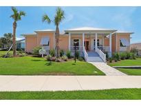 Charming peach-colored home with a welcoming front porch and beautifully landscaped yard at 1127 Fiesta Key Cir, Lady Lake, FL 32159