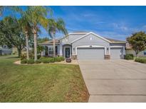 Charming single-story home with a well-manicured lawn, stone accents, three-car garage, and beautiful landscaping at 11601 Thacker Dr, Clermont, FL 34711