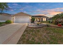 Charming single-story home featuring a well-maintained lawn, landscaped flower beds, and a two-car garage at 1282 Fort Lawn Loop, The Villages, FL 32162