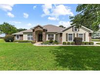 Charming single-story home with stone accents, manicured lawn, and lush landscaping at 12913 County Road 104B, Oxford, FL 34484