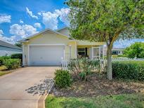 Charming home featuring a well-maintained yard with a cozy, covered front porch and attached two-car garage at 1406 Zest Ave, The Villages, FL 32163