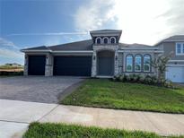 Charming single-story home with a three-car garage, paver driveway, and nicely landscaped front yard at 1849 Sunshine Peak Dr, Minneola, FL 34715