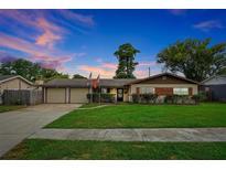 Charming ranch-style home with a well-manicured lawn, a two-car garage, and lush landscaping at 2007 Mosher Dr, Orlando, FL 32810