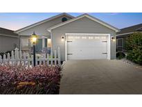 Charming gray home with a white garage door, white picket fence, and a cozy screened-in porch at 2142 Weber Ct, The Villages, FL 32163