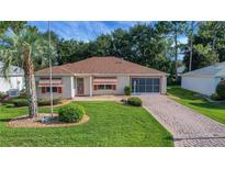 Charming home featuring a well-manicured lawn, brick driveway, and a cozy, inviting entrance at 2766 Privada Dr, The Villages, FL 32162