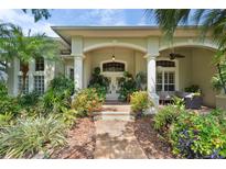 Welcoming front entrance with lush landscaping, white pillars, and comfortable outdoor seating area at 2904 Avalos Dr, The Villages, FL 32162