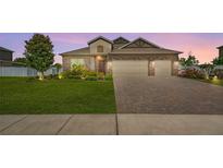 Charming single-Gathering home showcasing a well-manicured lawn and brick driveway at sunset at 3222 San Leo Dr, Orlando, FL 32820