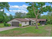 Charming single-story home with a well-manicured lawn, mature trees, and an attached two-car garage at 33 Palm Dr, Yalaha, FL 34797