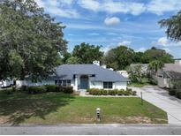 Charming single-story home features a well-manicured lawn, mature trees, and a welcoming entrance with a blue door at 33913 Sabal Way, Leesburg, FL 34748