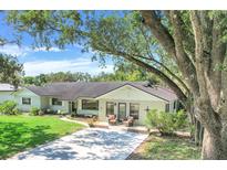 Charming single story home featuring a lush lawn, mature trees, and cozy front porch at 410 E Gulley Ave, Oakland, FL 34760