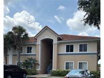 A two-story building with a tile roof and tan exterior features a welcoming entrance and mature landscaping at 508 Villa Del Sol Cir # 105, Orlando, FL 32824