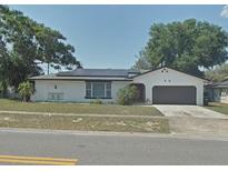 Charming single-story home featuring a two-car garage, well-maintained lawn, and mature trees at 6221 Ambassador Dr, Orlando, FL 32808