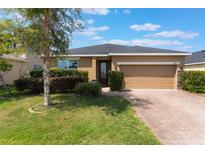 Charming single-story home boasts a manicured lawn, complemented by a two-car garage and brick-paved driveway at 686 Black Eagle Dr, Groveland, FL 34736