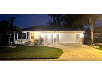 Charming single-story home with a well-manicured lawn, illuminated by exterior lights at dusk at 9430 Se 176Th Saffold St, The Villages, FL 32162