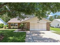 Charming single-story home with stone accents, lush lawn, and mature shade trees at 1011 Dundee Cir, Leesburg, FL 34788