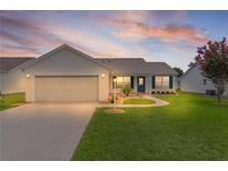 Charming single-story home with attached garage, walkway and manicured lawn against a colorful dusk sky at 1313 Arredondo Dr, The Villages, FL 32162