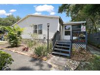 Charming single-story home featuring tidy landscaping, welcoming front porch and light gray siding at 13137 Kansas Ave, Astatula, FL 34705