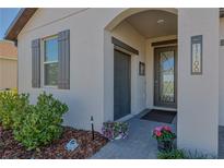 Charming front entrance with a gray-trimmed door, lovely plants, and an address plaque at 17108 Se 111Th Terrace Rd, Summerfield, FL 34491